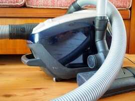 A steam cleaner connects its hoses to the nozzle which emits the moist air.